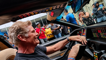 David Hasselhoff smiling behind the wheel of the KITT replica car during a cruise.